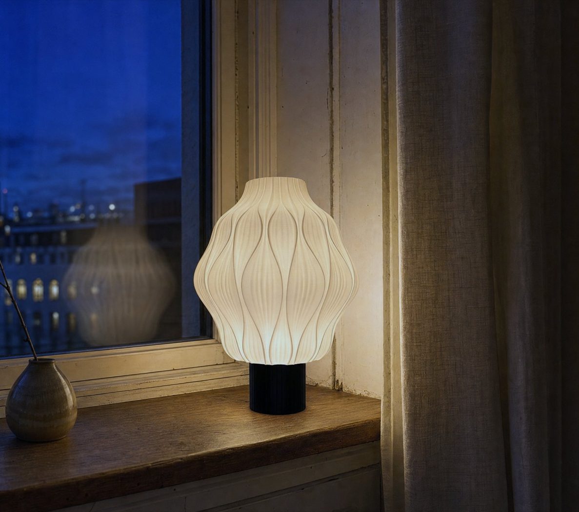 Lampa stołowa Petal Blossom zapalona na parapecie o zmierzchu